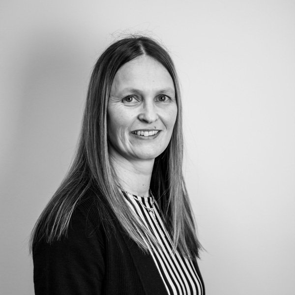 Nicole Bleasdale, Operational Support Manager poses for her professional profile picture in a black and white stripped top and black cardigan