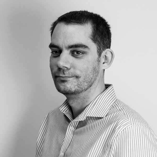 Tristan Hallett, Development Manager for SMAS Worksafe sits for his company profile picture in a blue and white stripped shirt